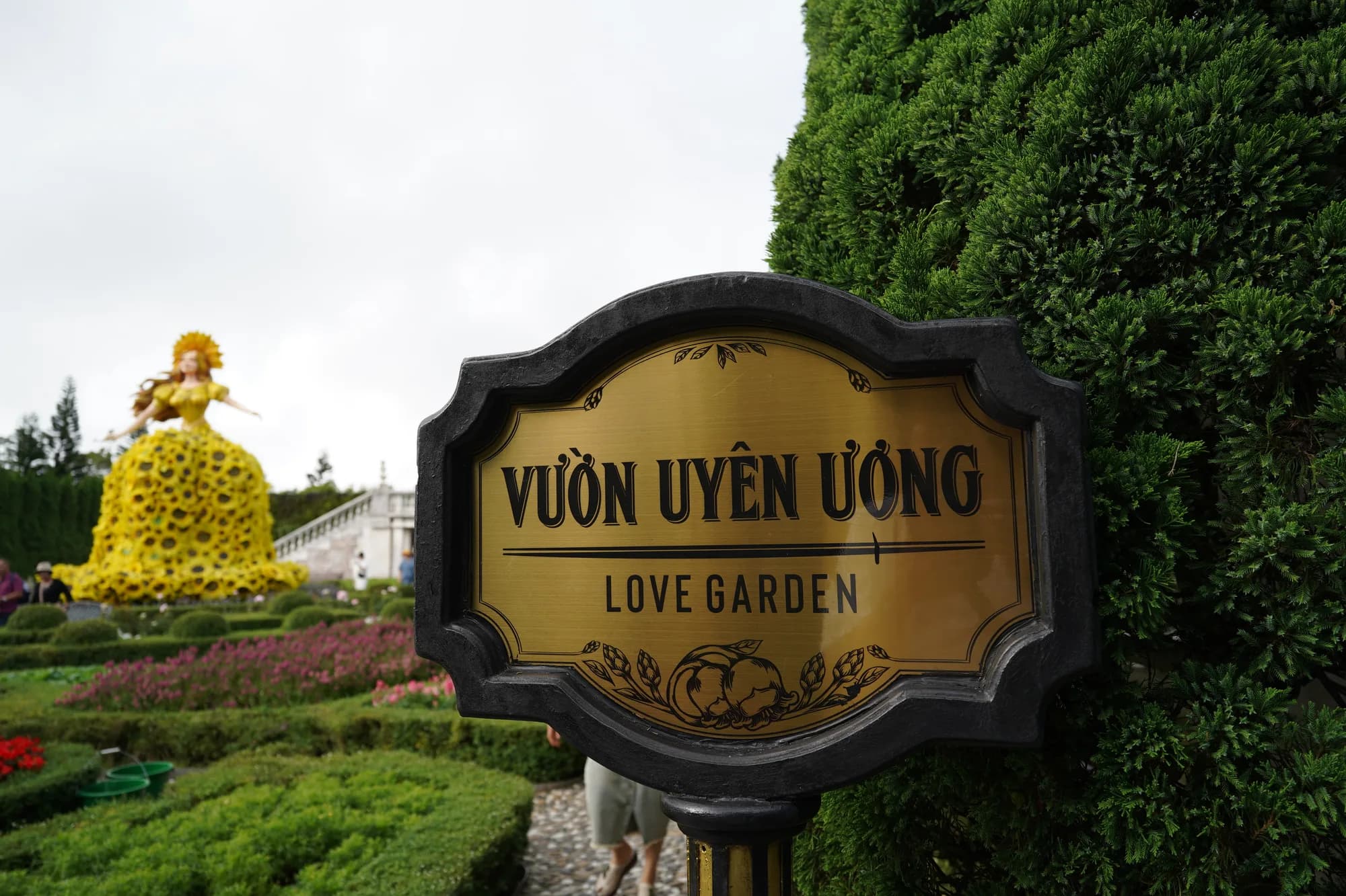 VƯỜN UYÊN ƯƠNG LOVE GARDEN と書かれた看板と、花壇の庭園